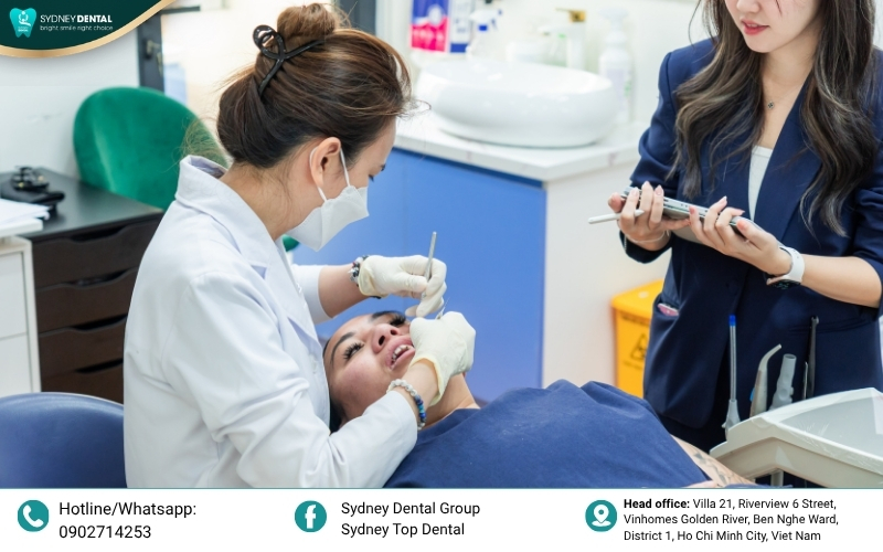A patient demonstrating proper daily oral hygiene using a water flosser and special interdental brush around the dental implant abutment.